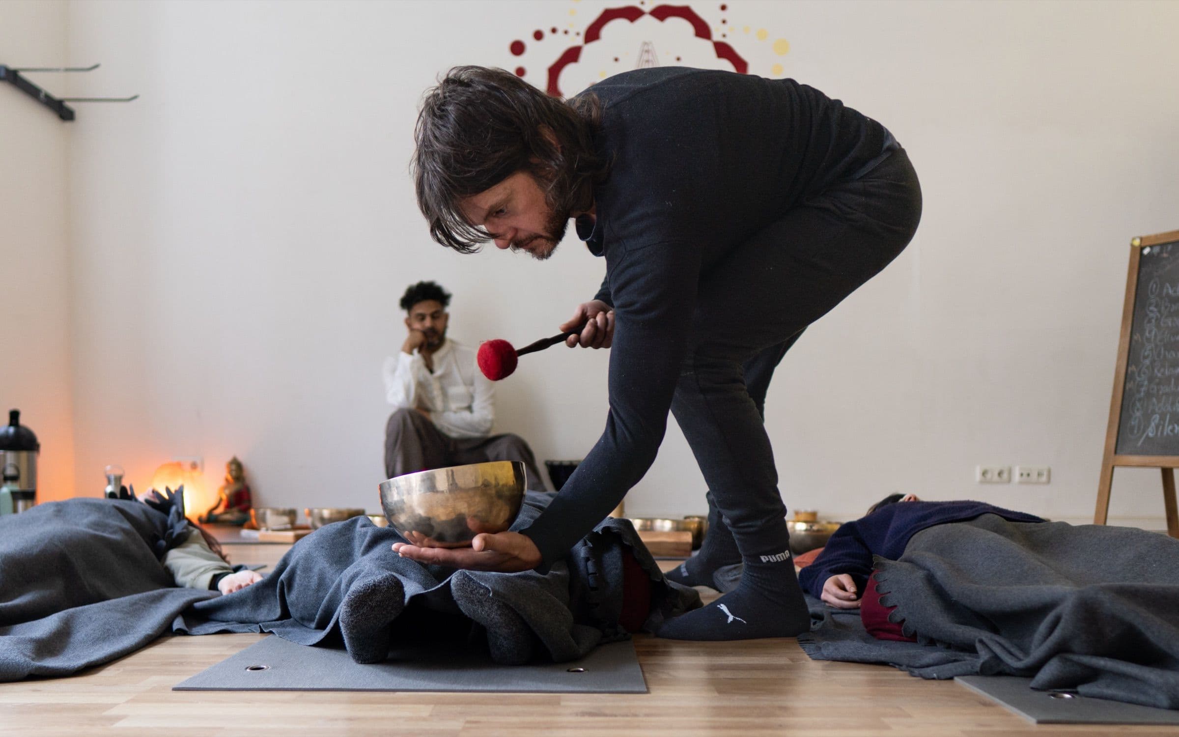 A singing bowl played above a participant lying down during a sound healing session