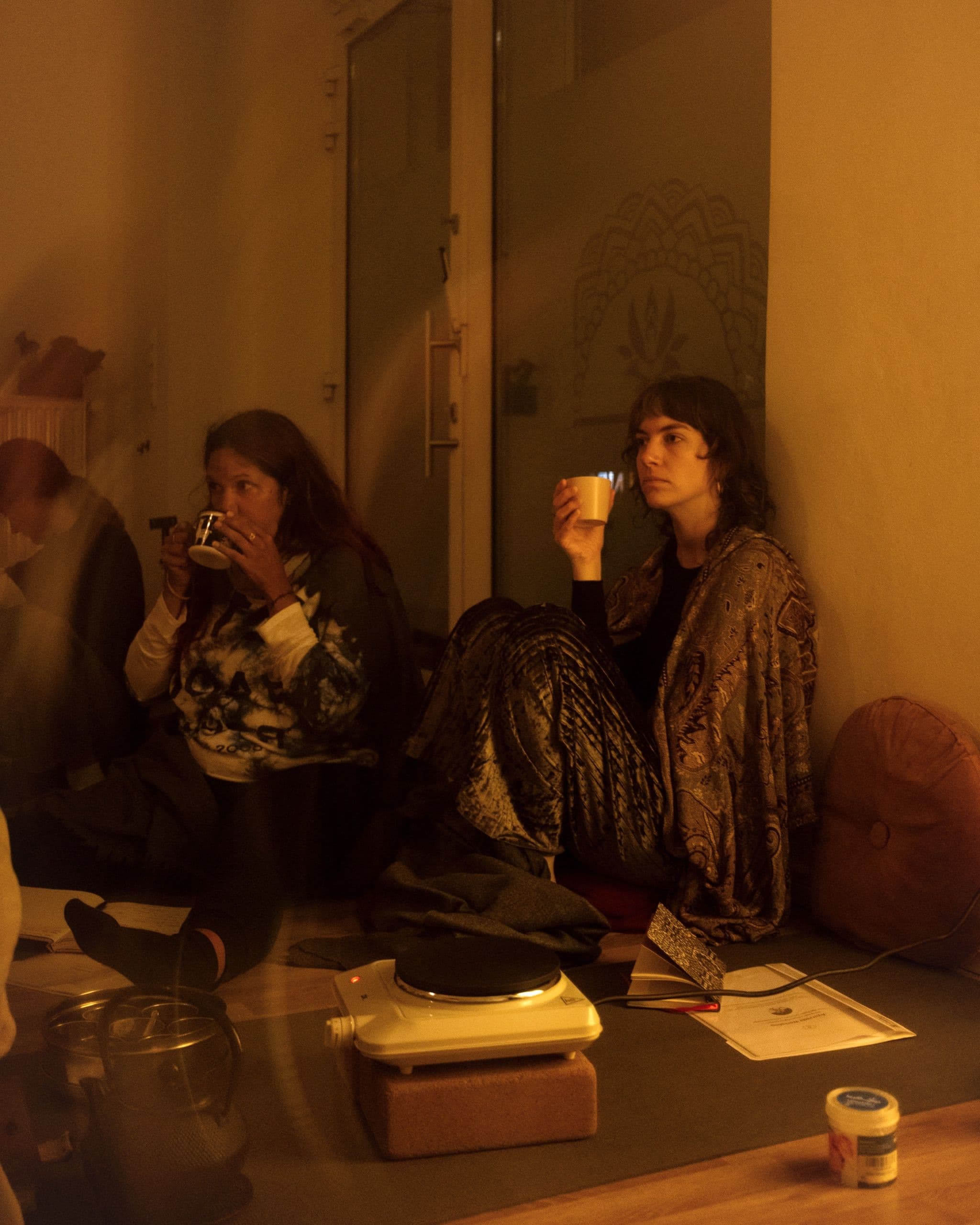 Two participants drinking tea in the warm light of the Yogicescape studio