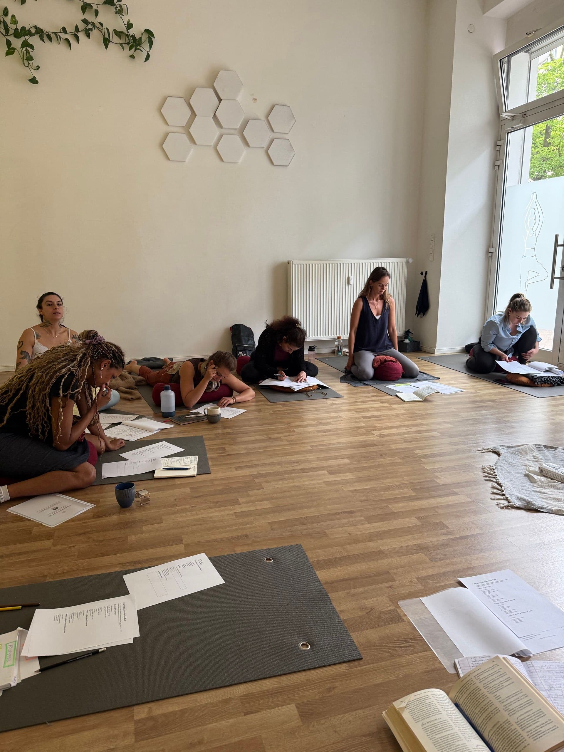 Participants working with notes and study materials on their yoga mats