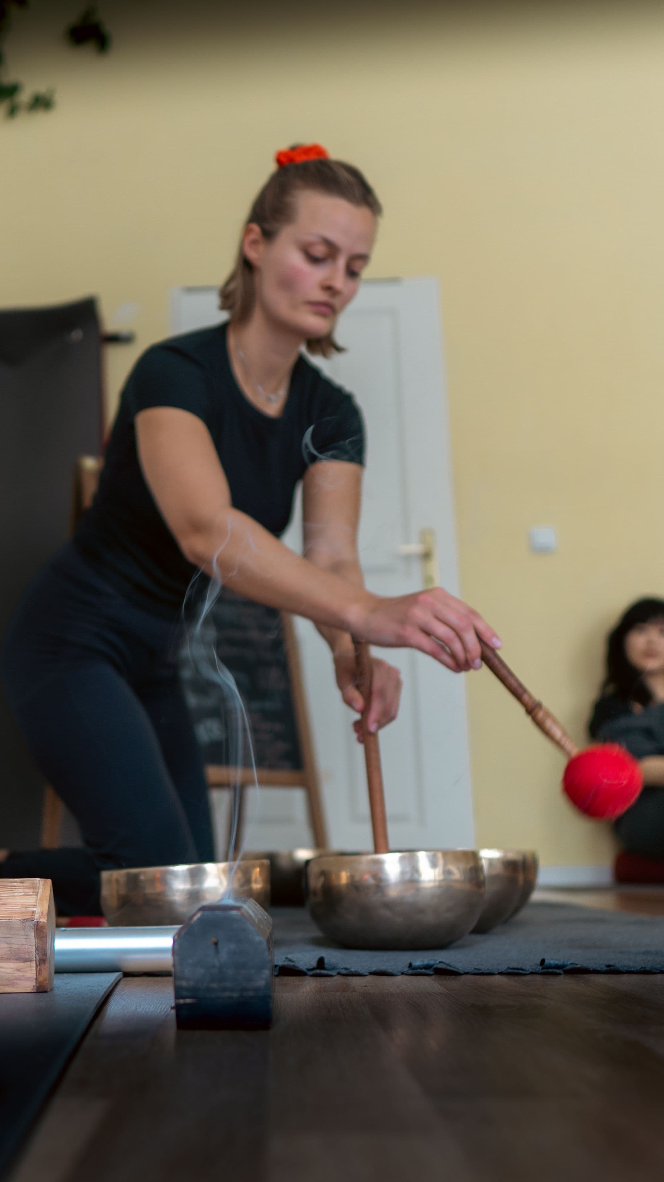 Junge Frau ruht auf einem roten Bolster neben einer Klangschale während der Klangheilungs-Ausbildung