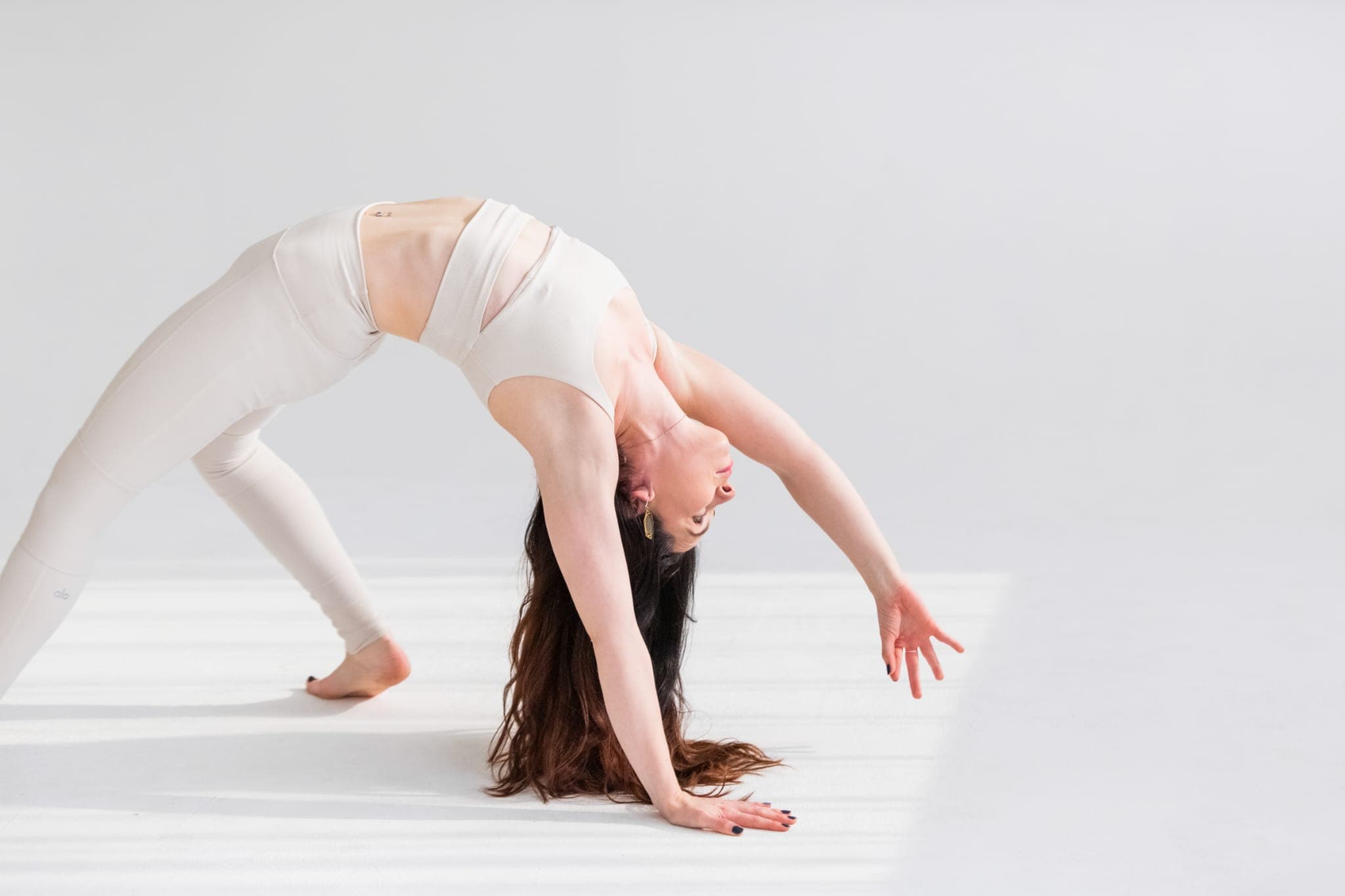 Eithne McGonigle in wild thing pose, a flowing one-armed backbend, dressed in white
