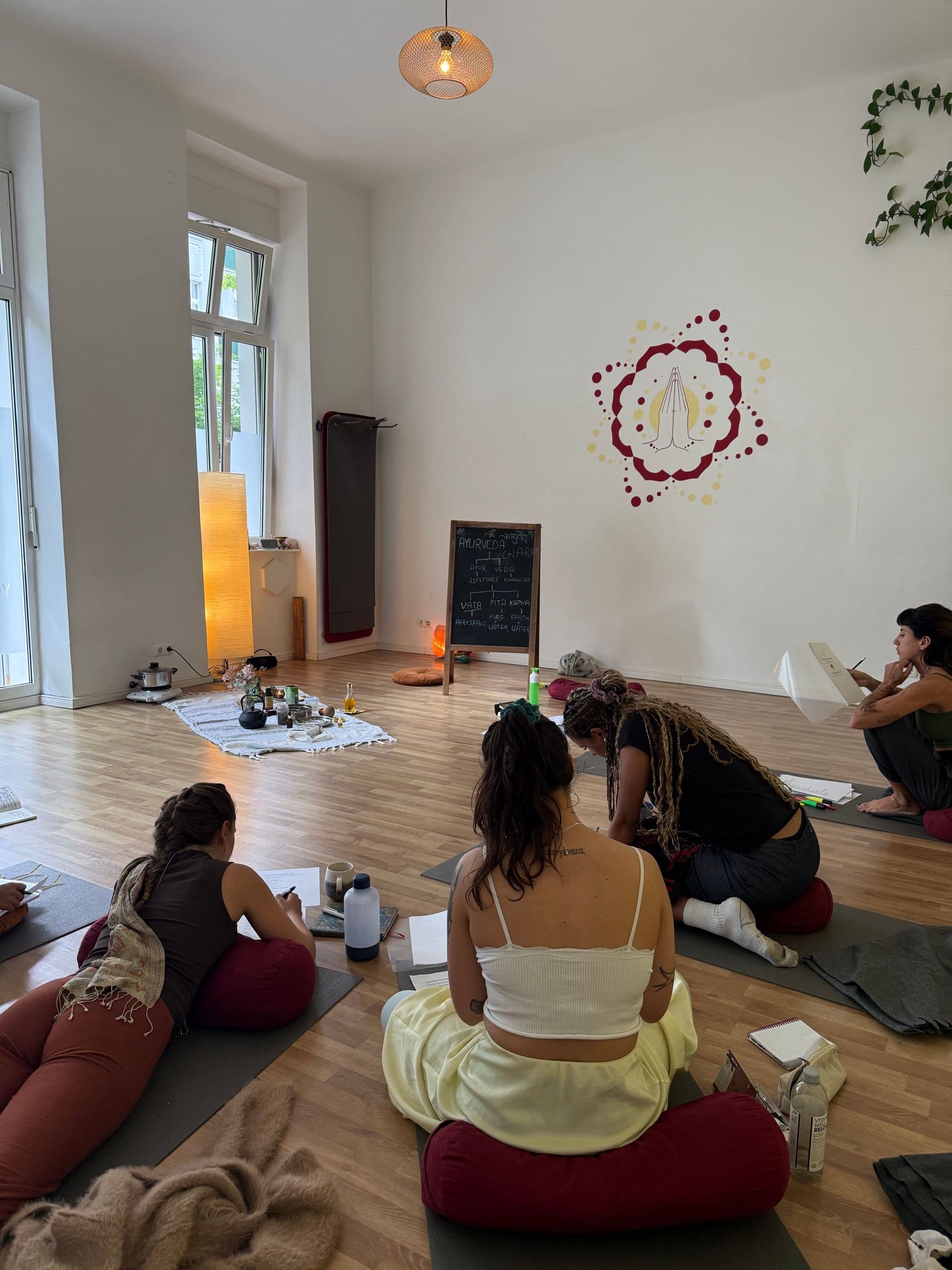 Participants with study materials beside a Dosha blackboard during an Ayurveda workshop